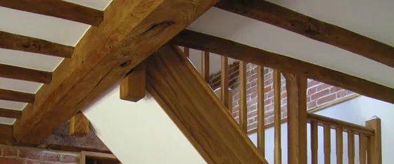 Oak beams and an oak staircase in a barn conversion, against old brickwork