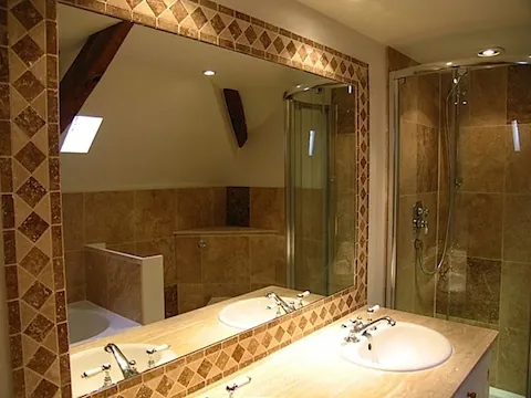 A bathroom in the barn conversion, with a framed mirror, basin and glass shower