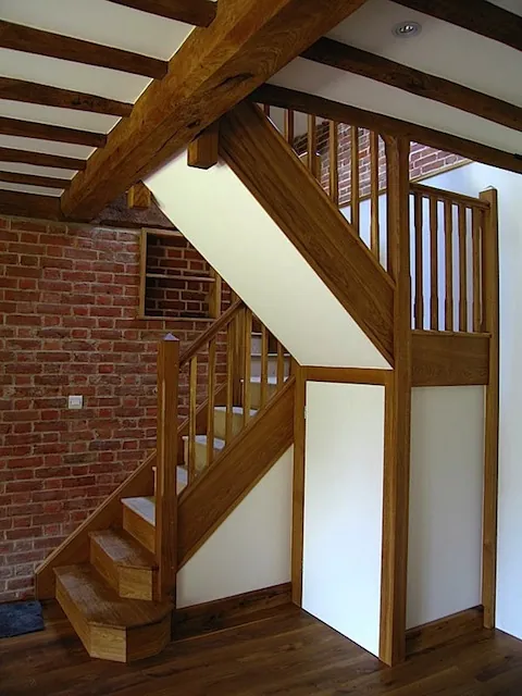 An oak staircase and balustrade in a listed barn conversion, under exposed beams
