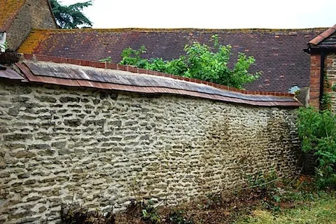 A long stone wall repointed in lime mortar, with its capping rebuilt